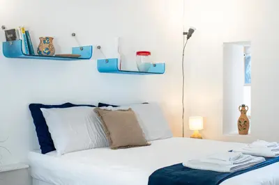a bedroom with a white bed with blue shelves on the wall at Studio Anatólio in Castellammare del Golfo