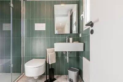 a green bathroom with a toilet and a sink at GuestHost - Alle Terrazze Blu - Mondello Sea View Apartment in Palermo