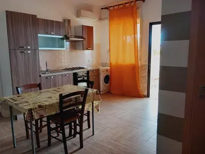 a kitchen with a table and chairs and a kitchen with an orange curtain at Residence Marino in Balestrate
