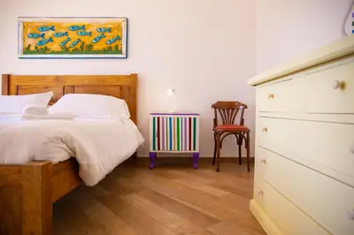 a bedroom with a bed and a dresser and a chair at Solemar Sicilia - Villa Mariù in Palermo