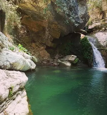 a pool of green water next to a waterfall at Affittacamere La Cartiera in Palazzo Adriano
