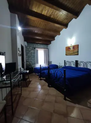 a bedroom with two beds and a stone wall at Affittacamere La Cartiera in Palazzo Adriano