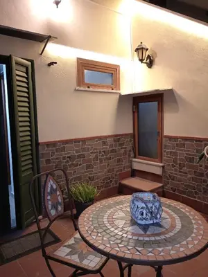 a patio with a table and chairs and a stone wall at La casetta di Giò Giò appartamento in centro a Monreale in Monreale