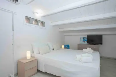 a white bedroom with a large bed and a tv at Sky Terrace Mondello Beach house in Palermo