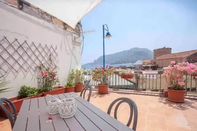 a wooden table and chairs on a balcony with flowers at Sky Terrace Mondello Beach house in Palermo