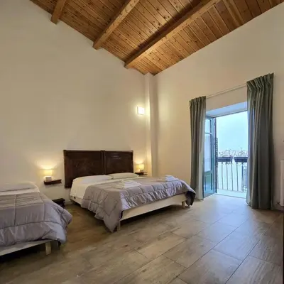 a bedroom with two beds and a large window at Downtown Maqueda in Palermo