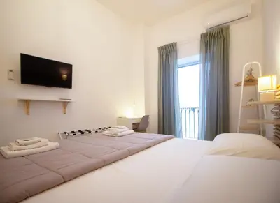a white bedroom with two beds and a flat screen tv at Downtown Maqueda in Palermo