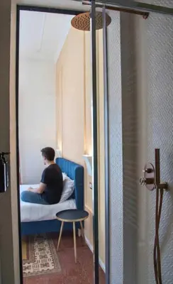 a man sitting on a bed in a small room at Suites Cavour holiday dream in Palermo