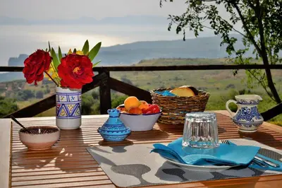 a table with vases and bowls of fruit and flowers at B&B Tre Giummare in Scopello