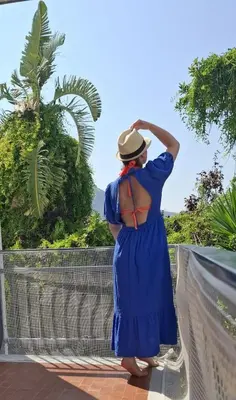 a woman in a blue dress and hat standing on a balcony at La casa di Gisa&Laura Lido di Mondello spiaggia in Palermo
