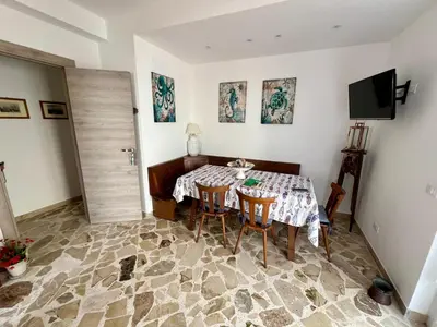 a dining room with a table and chairs and a television at La casa di Gisa&Laura Lido di Mondello spiaggia in Palermo