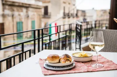 a table with a glass of wine and a plate of pastries at Casa Alexandra - Luxury & Design in Castellammare del Golfo