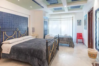 a bedroom with a bed and a red chair at Federico 70 Arabic Style in Palermo