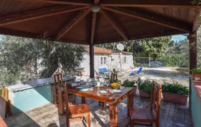 a patio with a table and chairs under a wooden umbrella at Lovely Home In Altavilla Milicia in Altavilla Milicia