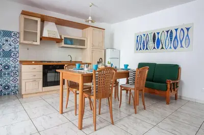 a kitchen with a wooden table and chairs and a kitchen with a kitchen at Appartamento del centro CIR 19081005C217988 in Castellammare del Golfo