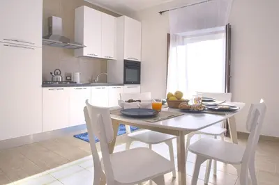 a kitchen with a table and chairs and a kitchen with white cabinets at Appartamento della macina CIR 19081005C212931 in Castellammare del Golfo