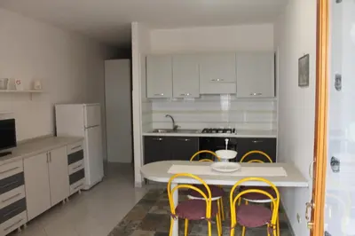 a kitchen with a table and yellow chairs in it at Turisti a Casa in San Vito lo Capo