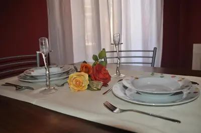 a table with plates and glasses and flowers on it at B&T Holiday House in Palermo
