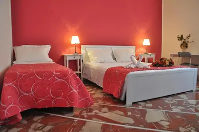 a bedroom with two beds and a red wall at B&T Holiday House in Palermo