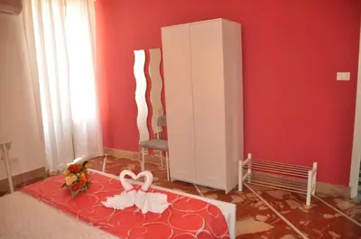 a room with a red wall and a cabinet and flowers at B&T Holiday House in Palermo