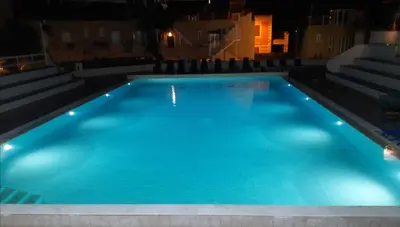 a large blue swimming pool at night at casa giorgia mondello in Palermo