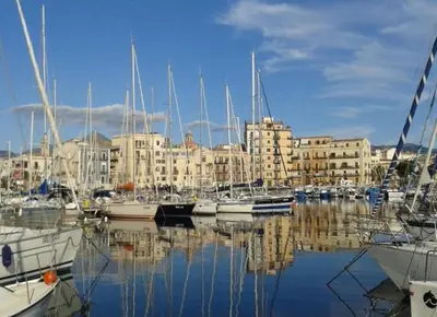 a group of boats docked in a harbor with buildings at casa giorgia mondello in Palermo