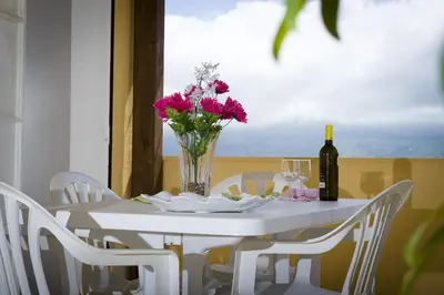 a white table with a vase of flowers and a bottle of wine at Casa Vacanza Saraceno in Castellammare del Golfo