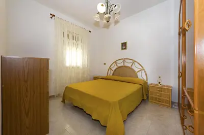 a bedroom with a bed with a yellow bedspread at Casa Vacanza Saraceno in Castellammare del Golfo