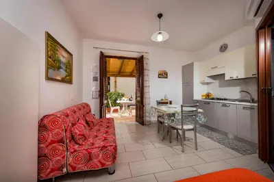 a living room with a red couch and a kitchen at Casa Vacanza Saraceno in Castellammare del Golfo