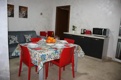 a dining room table with red chairs and a table with fruit on it at Sweet Home Pietro e Lia by Holiday World in Casteldaccia