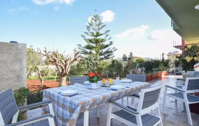 a table and chairs on a patio with a tree at Nice Apartment In Portella Di Mare in Portella di Mare