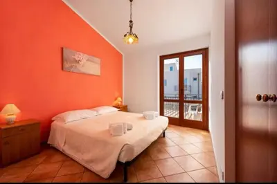 a bedroom with a bed with an orange wall at Marconi in San Vito lo Capo