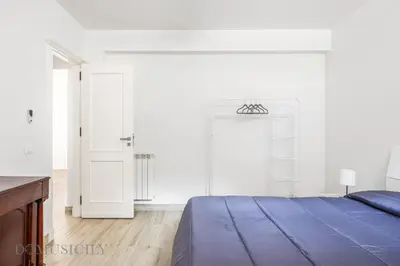 a white bedroom with a blue bed and white walls at La Dimora del Mare by Domus Sicily in Mondello