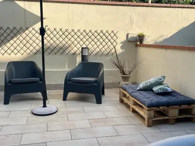 a patio with two chairs and a bench and an umbrella at Flat with Terrace & Pool in Mondello