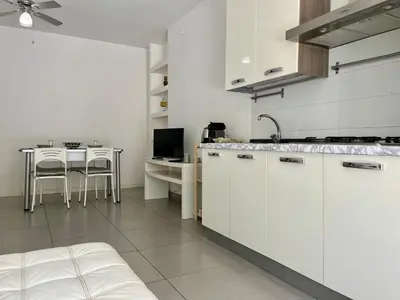 a kitchen with white cabinets and a table in it at Flat with Terrace & Pool in Mondello