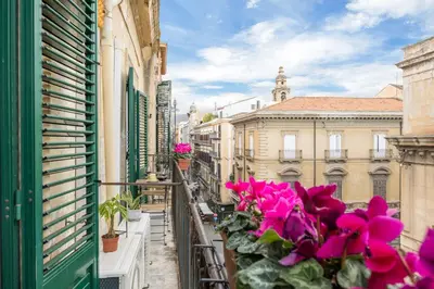 a balcony with pink flowers on a city street at 70 Lab Apartment in Palermo