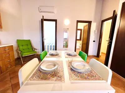 a dining room table with a white tablecloth and chairs at Casa Carlotta Apartments in Terrasini