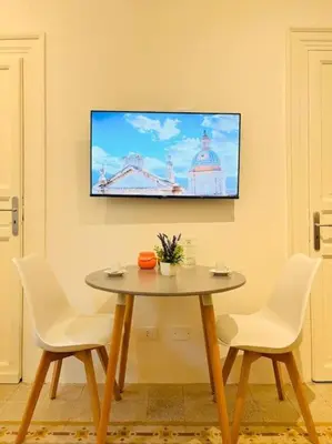 a table with two chairs and a tv on a wall at Corte del Tribunale in Palermo