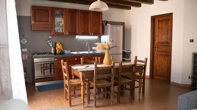 a kitchen with a wooden table and chairs and a kitchen with a refrigerator at Appartamento in Centro Storico a Termini Imerese - Eden Holiday Home in Termini Imerese