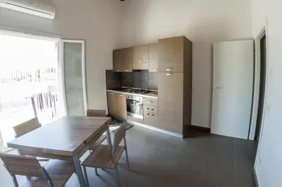 a kitchen with a wooden table and chairs in a room at Villa Giambona in Isola delle Femmine