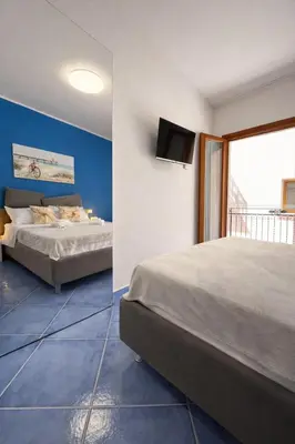 a bedroom with two beds and a tv on the wall at Oikos Design Sicily in Castellammare del Golfo