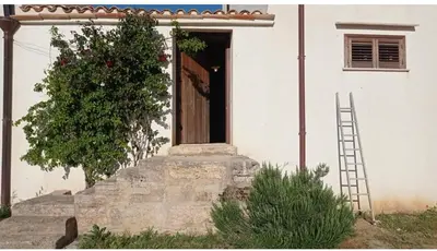 a door of a white house with a ladder at casa di campagna iobio in Alcamo