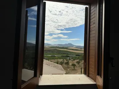 an open window with a view of a field at casa di campagna iobio in Alcamo