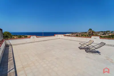 two chairs on a patio with the ocean in the background at Villa con Piscina sul Mare a Terrasini in Terrasini