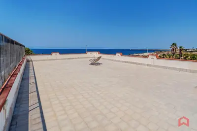 a bench sitting on a wall next to the ocean at Villa con Piscina sul Mare a Terrasini in Terrasini