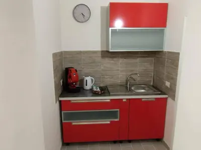 a red kitchen with a sink and a clock at Casa Veni Ka in Palermo