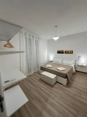 a white bedroom with a bed and a table at Casa Andrew in Terrasini