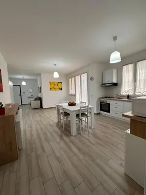 a living room with a table and a kitchen at Casa Andrew in Terrasini