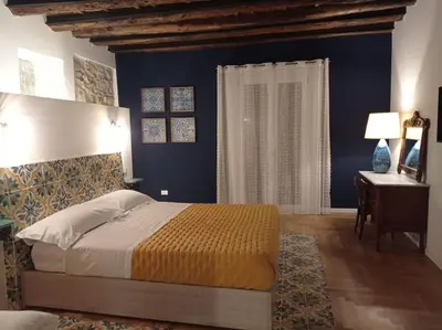 a bedroom with a bed and a desk and blue walls at Casa Verderame in Palermo