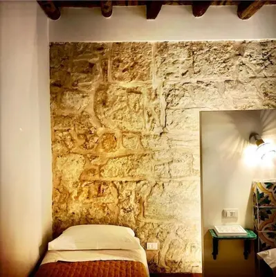 a bedroom with a stone wall with a bed at Casa Verderame in Palermo